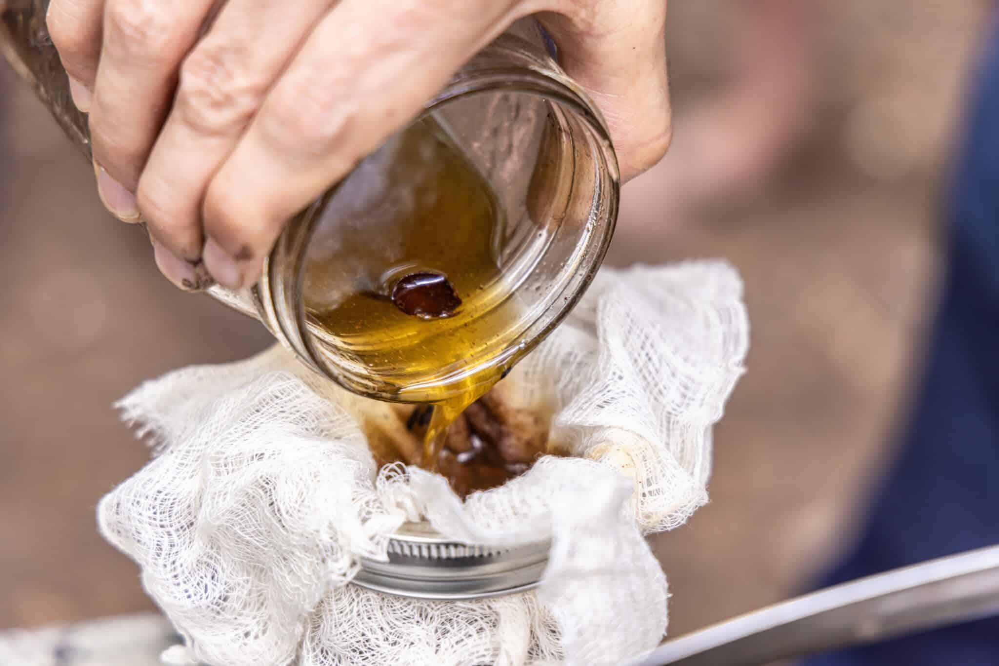 Herbalist,Is,Pouring,A,Homemade,Herbal,Extract,Through,A,Cheesecloth tincure straining