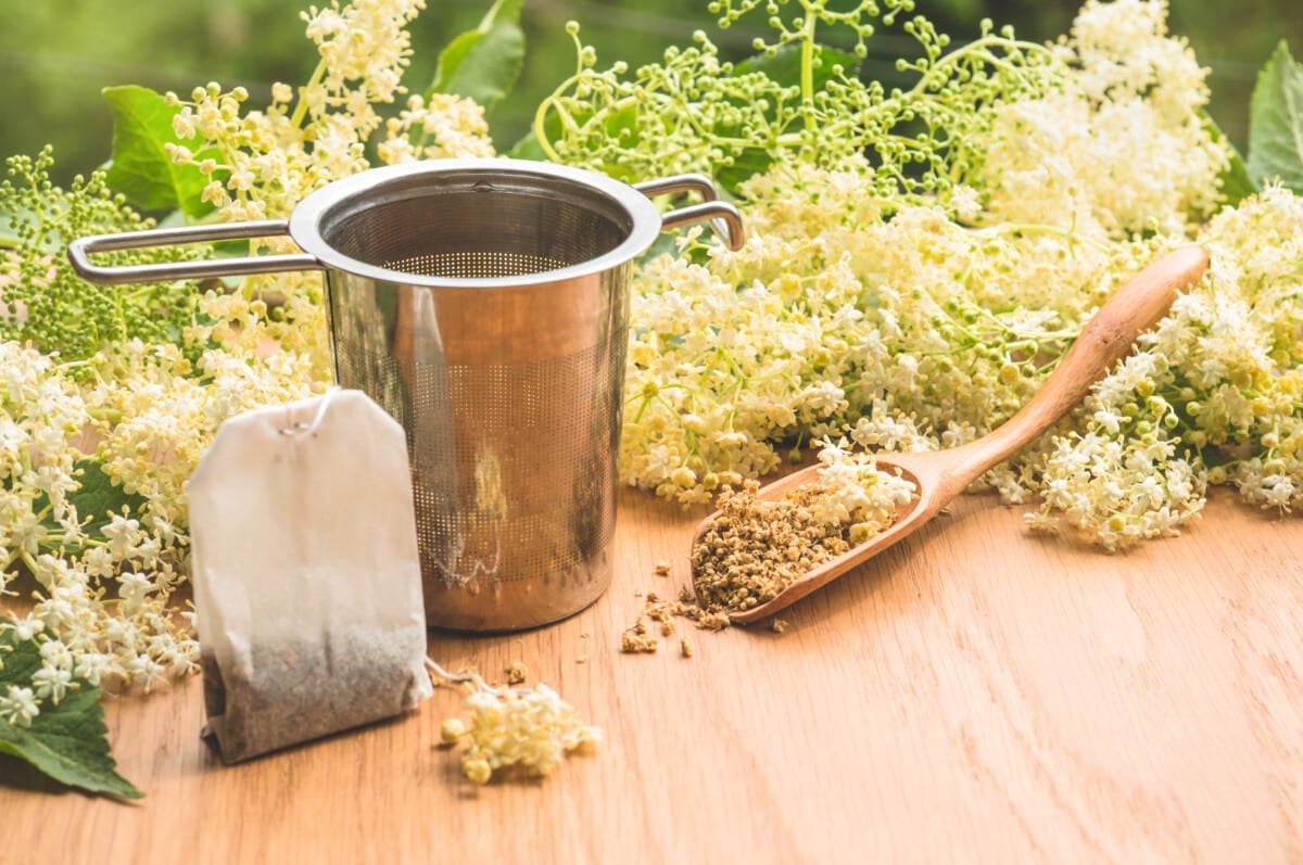 an elderberry tea bag and strainer with a wooden spoon next to a bag of elderberry tea