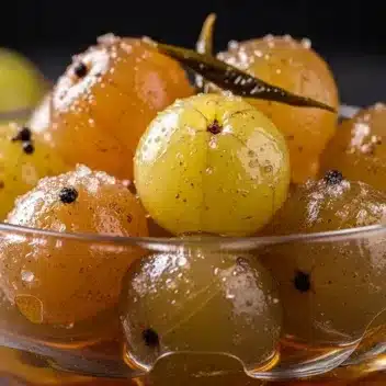 Amla (Phyllanthus emblica) murabba — whole amla preserved in syrup with spices in a glass bowl